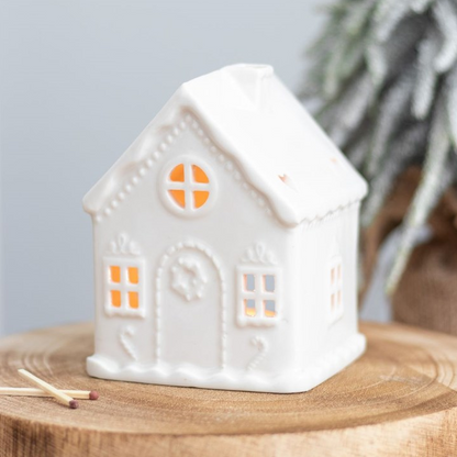 White ceramic house-shaped lantern on a wooden surface with a light gray background