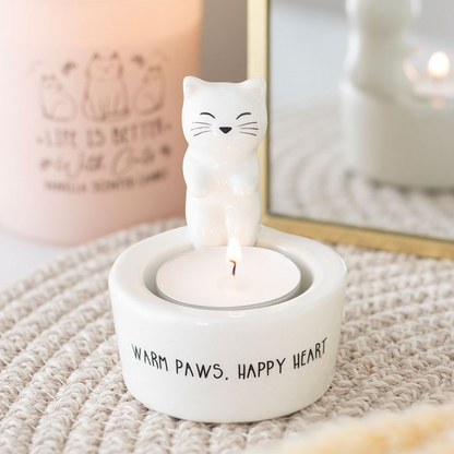 Candle holder with a cat-shaped candle and 'Warm paws. Happy heart.' text on a textured surface.