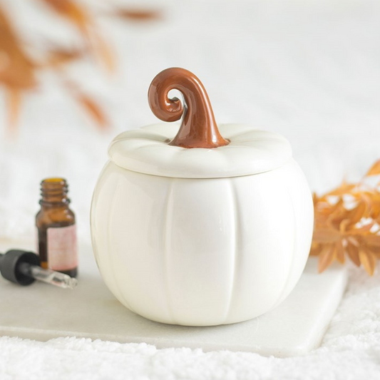White ceramic pumpkin with a brown top on a white surface with blurred background