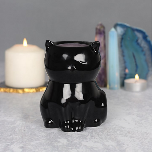 Black cat-shaped candle holder on a gray surface with candles and crystals in the background.