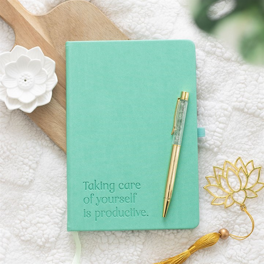 Mint green notebook with a pen on a textured surface with decorative elements.