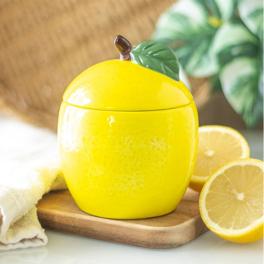 Yellow lemon-shaped container with a lid on a wooden board with lemons in the background.