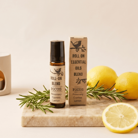 A roll-on essential oil blend bottle and its matching cardboard box, both labeled 'FOCUS Rosemary Cypress Lemon,' styled on a marble board with lemon slices, rosemary sprigs, and two whole lemons against a warm cream background.