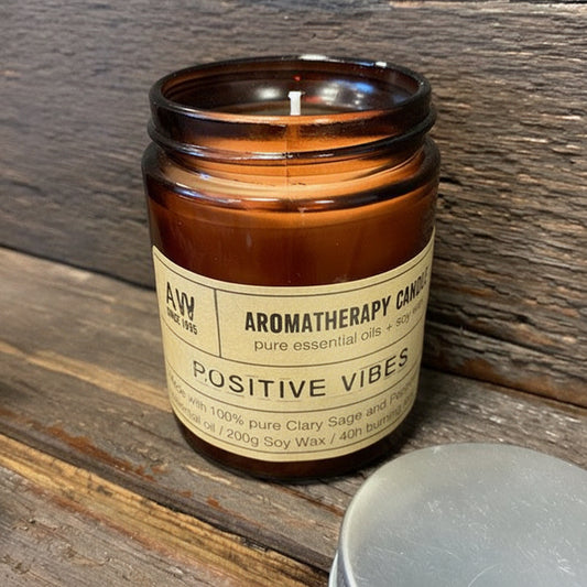 Aromatherapy candle labeled 'Positive Vibes' on a wooden surface