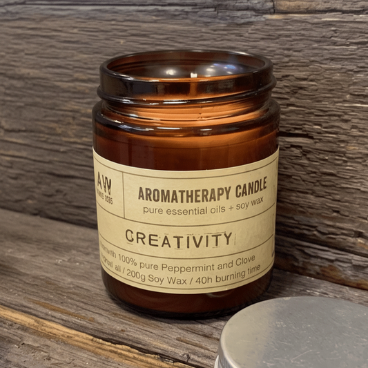 An amber glass jar candle labeled 'Aromatherapy Candle Creativity' by A4W Candle Co, styled on a rustic wooden surface with lavender sprigs and a silver metal lid in the foreground.