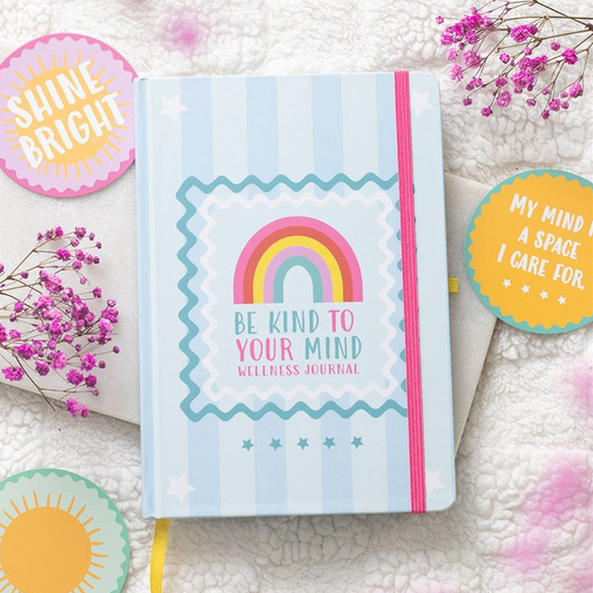 Journal with rainbow design and motivational text on a soft surface with decorative elements.