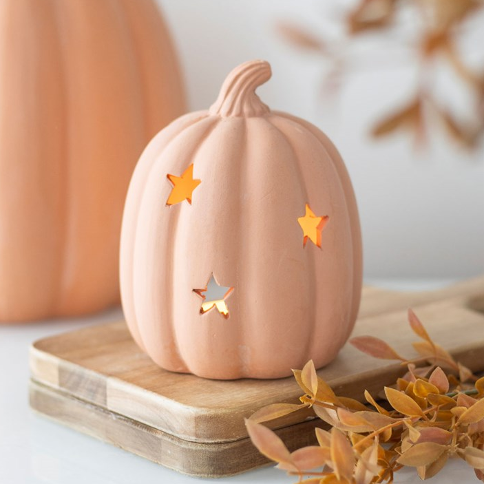 Decorative pumpkin with star cutouts on a wooden surface with a blurred background