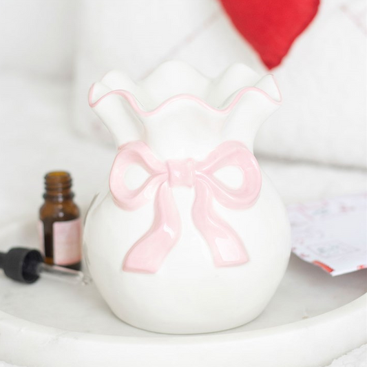 White ceramic jar with a pink bow on a white surface with a blurred background