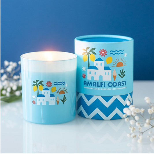 Two blue candles with 'Amalfi Coast' design on a white surface with a blue background
