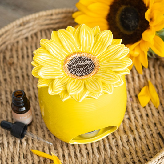 Yellow flower-shaped diffuser on a textured surface with a sunflower in the background