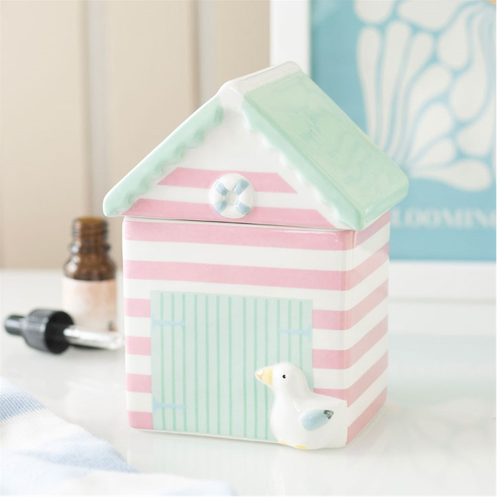 Pastel striped birdhouse with a small duck figurine on a white surface.