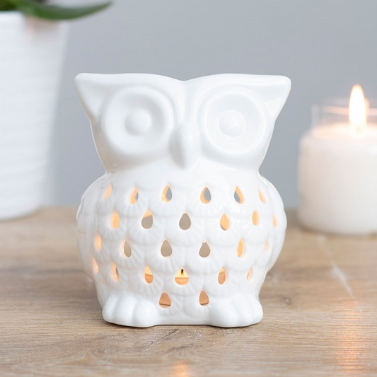 White owl-shaped ceramic lantern with a candle inside on a wooden surface.