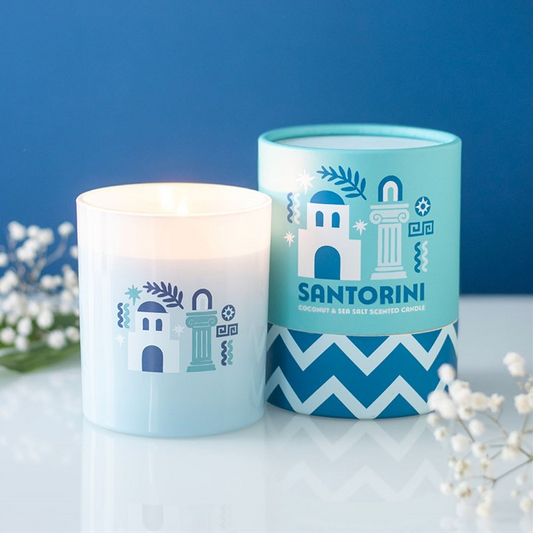 Candle and decorative container with Santorini design on a white surface with blue background
