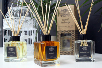 Three diffusers with reeds and bottles on a surface, with a blurred background.